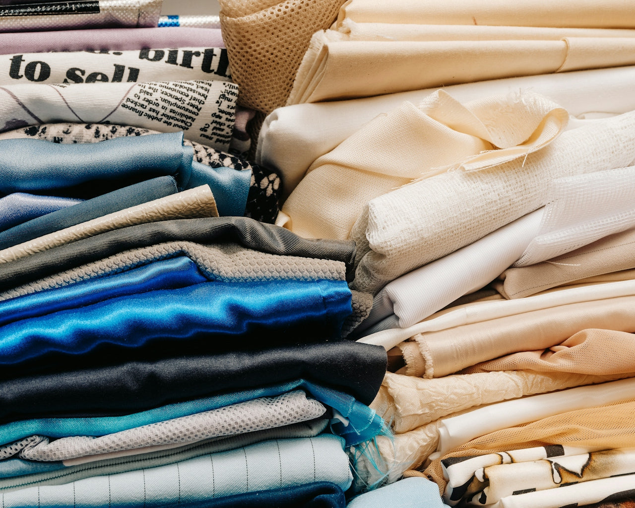 Various fabrics and colorful clothes stacked haphazardly, illustrating an overflowing wardrobe in need of a clean-out.